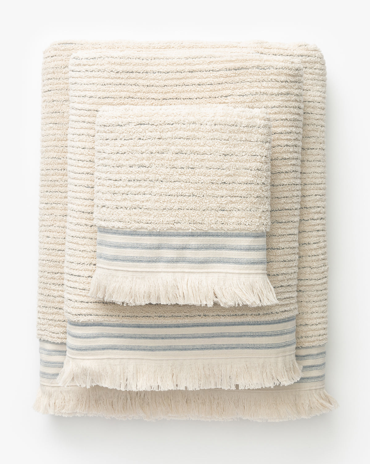 Three hand towels from the Frayser Bath Collection, made of Turkish cotton with textured stripes and fringe edges. Blue-gray and white bands near the ends add a decorative touch, by McGee & Co.
