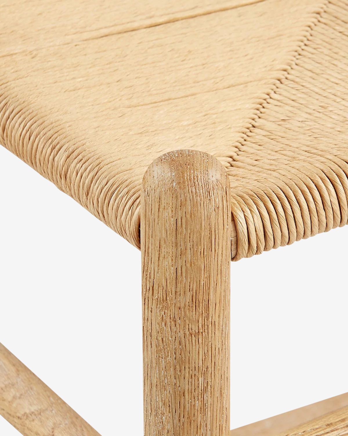 Close-up of the Gabriel Counter Stool’s corner, featuring a natural wood frame and light tan rope seat with a diagonal weave pattern, inspired by Scandinavian Modernism, by McGee & Co.