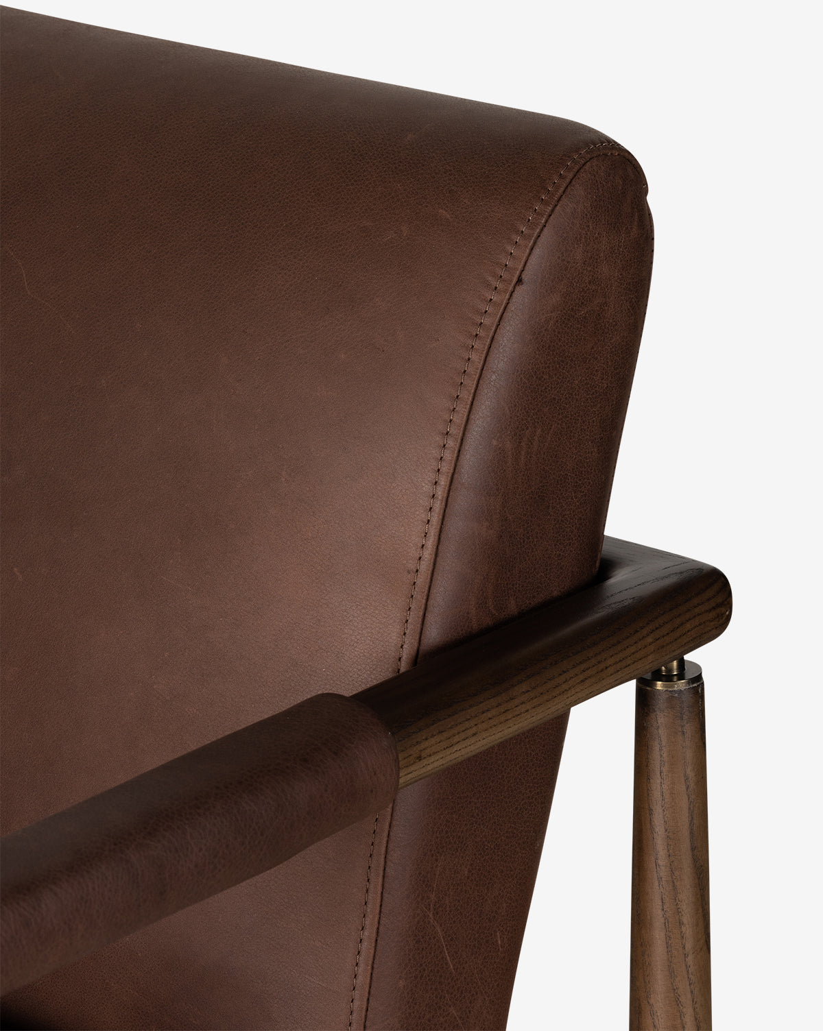 Close-up of the Gaston Lounge Chair, showcasing its solid ash frame, detailed stitching, and textured top grain leather upholstery on the wooden armrests and support, by McGee & Co.