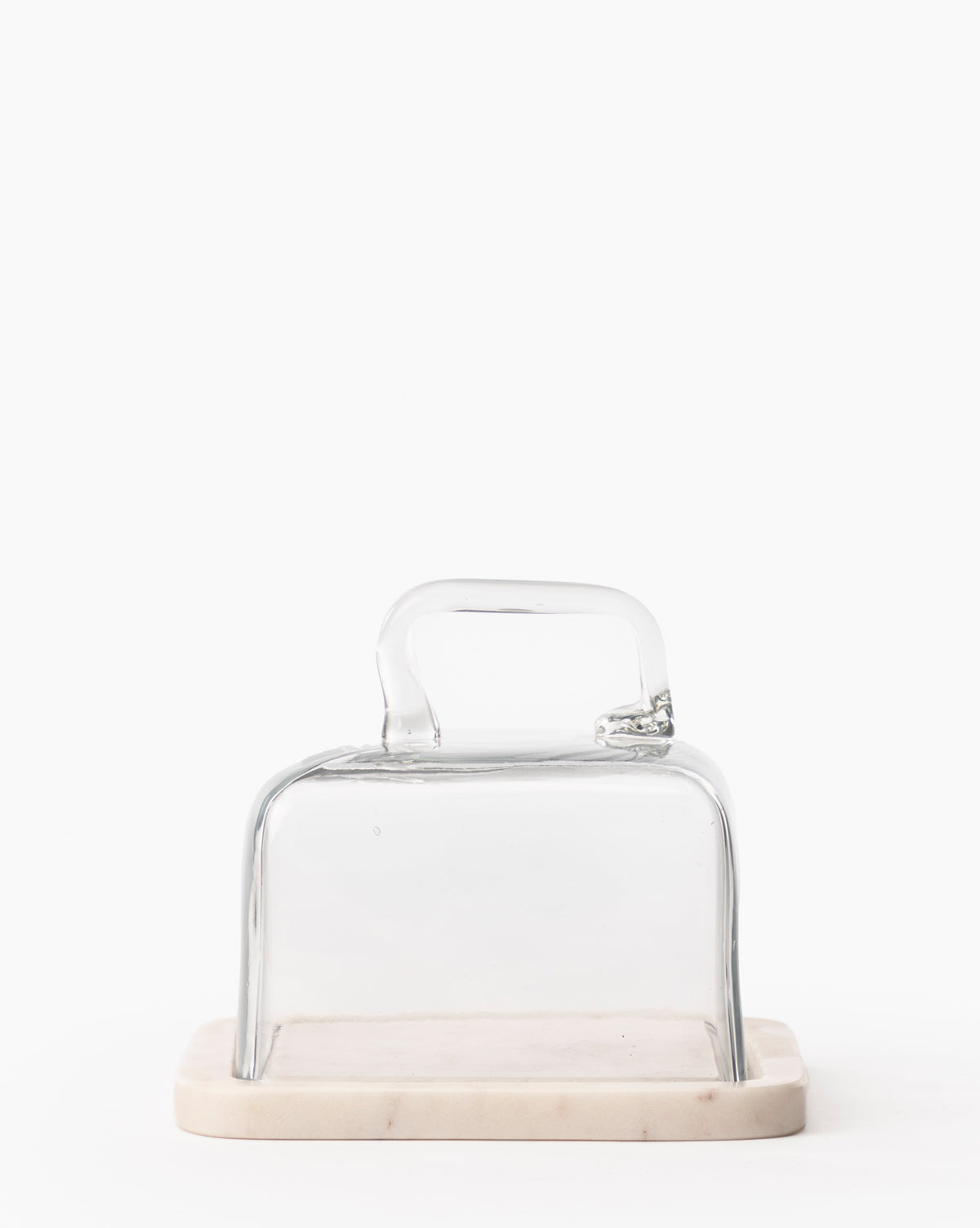The Glass & Marble Cloche features a square glass cover with handle on a rectangular marble base, creating an elegant kitchen accessory thats beautifully showcased against a plain white background, by McGee & Co.