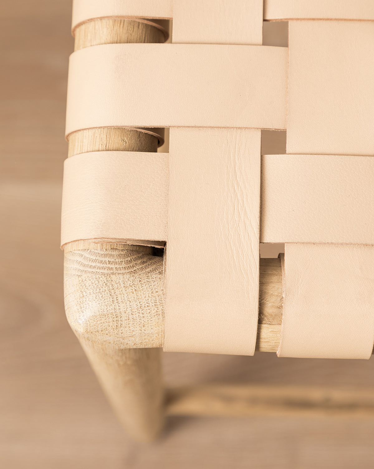 Close-up of the Greely Stools corner, featuring natural aniline-dyed leather straps woven in a crisscross pattern on a white oak frame, showcasing the rich textures of both materials, by McGee & Co.