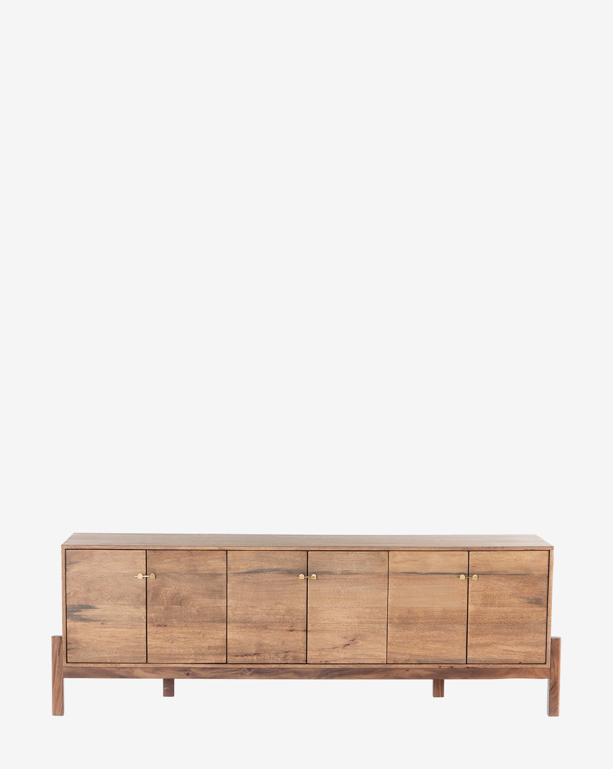 The Gustav Console is a low, rectangular piece with four cabinet doors, small gold handles, and short legs. Its natural rustic wood finish and discreet media cord management make it ideal for mid-century style interiors, by McGee & Co.