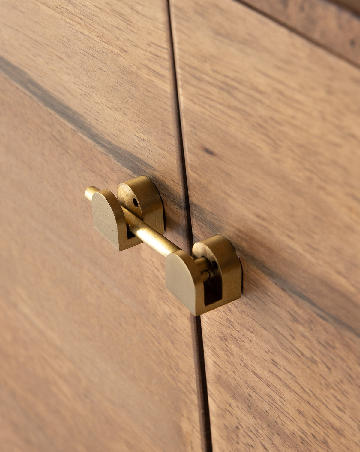 Close-up of the Gustav Console’s brass latch securing two wooden doors, highlighting the wood grain, modern hardware, and built-in media cord management features, by McGee & Co.