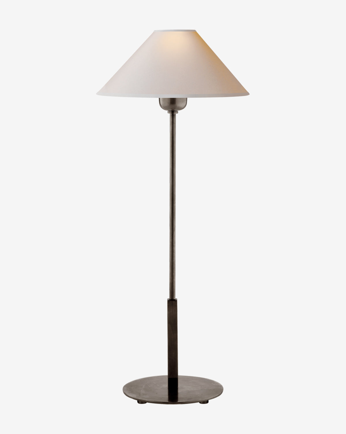The Hackney Table Lamp by Visual Comfort & Co. Signature features a slim dark brass body, a wide white linen shade, and a minimalist, elegant design that softly glows against a plain white background. McGee & Co.