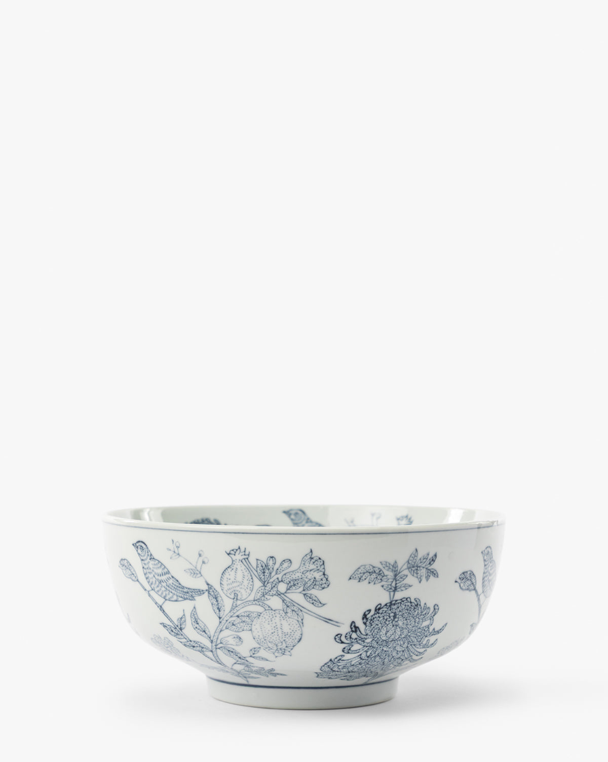 Hand Stamped Botanical Bowl features delicate blue bird motifs and floral patterns on white porcelain, creating an elegant contrast against a plain background, by McGee & Co.