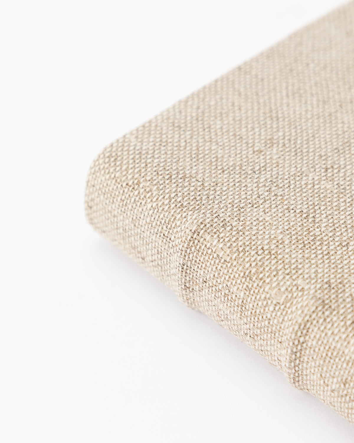 Close-up of the Handcrafted Linen Book’s corner against a white background, showcasing its beige linen fabric texture and traditional binding.