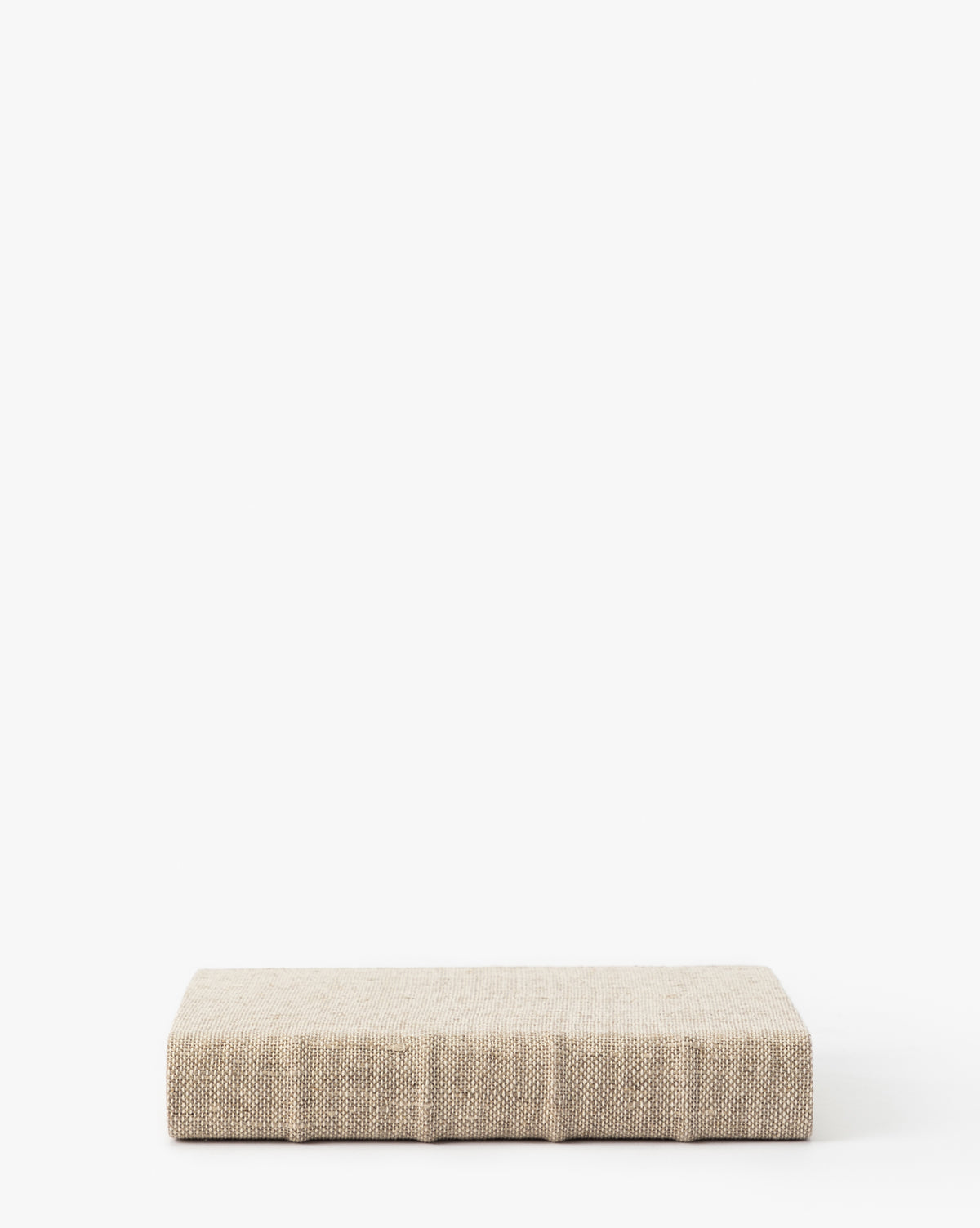 A handcrafted linen book with a rectangular, minimalist beige cover and a textured surface is shown on a white background, featuring no visible patterns or embellishments.
