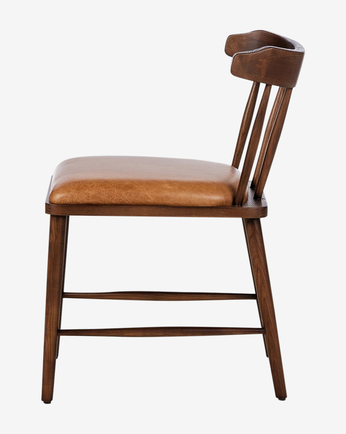 Side view of the Harper Dining Chair: solid ash frame, curved backrest, spindle supports, and brown leather upholstered seat. This chair features clean lines and a slightly angled back in a simple mid-century modern style, by McGee & Co.