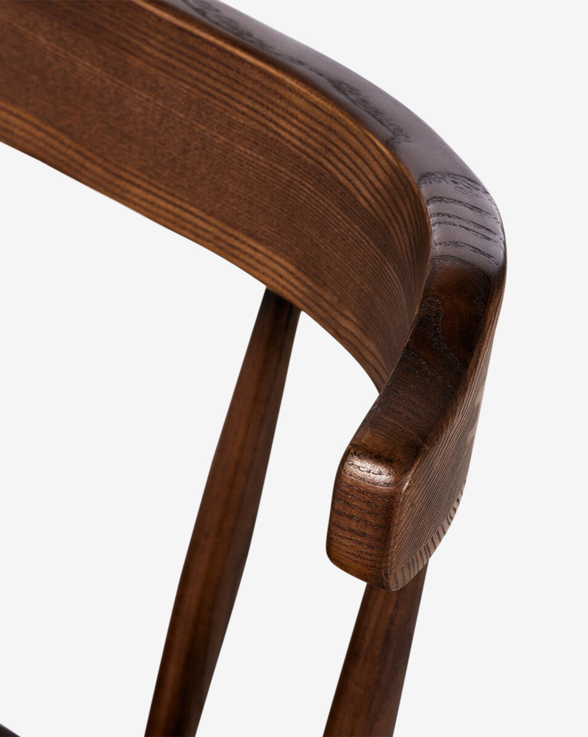 Close-up of the Harper Dining Chair’s curved backrest, showcasing smooth, dark brown solid ash wood grain and craftsmanship against a white background, by McGee & Co.