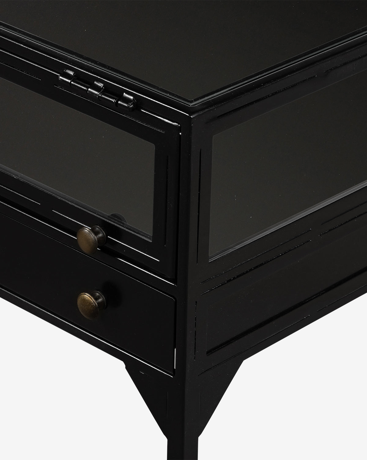 Close-up of the Harry Nightstand, featuring a black metal shadowbox design with glass panels, two round metal drawer knobs, and angular legs, displayed against a plain white background.