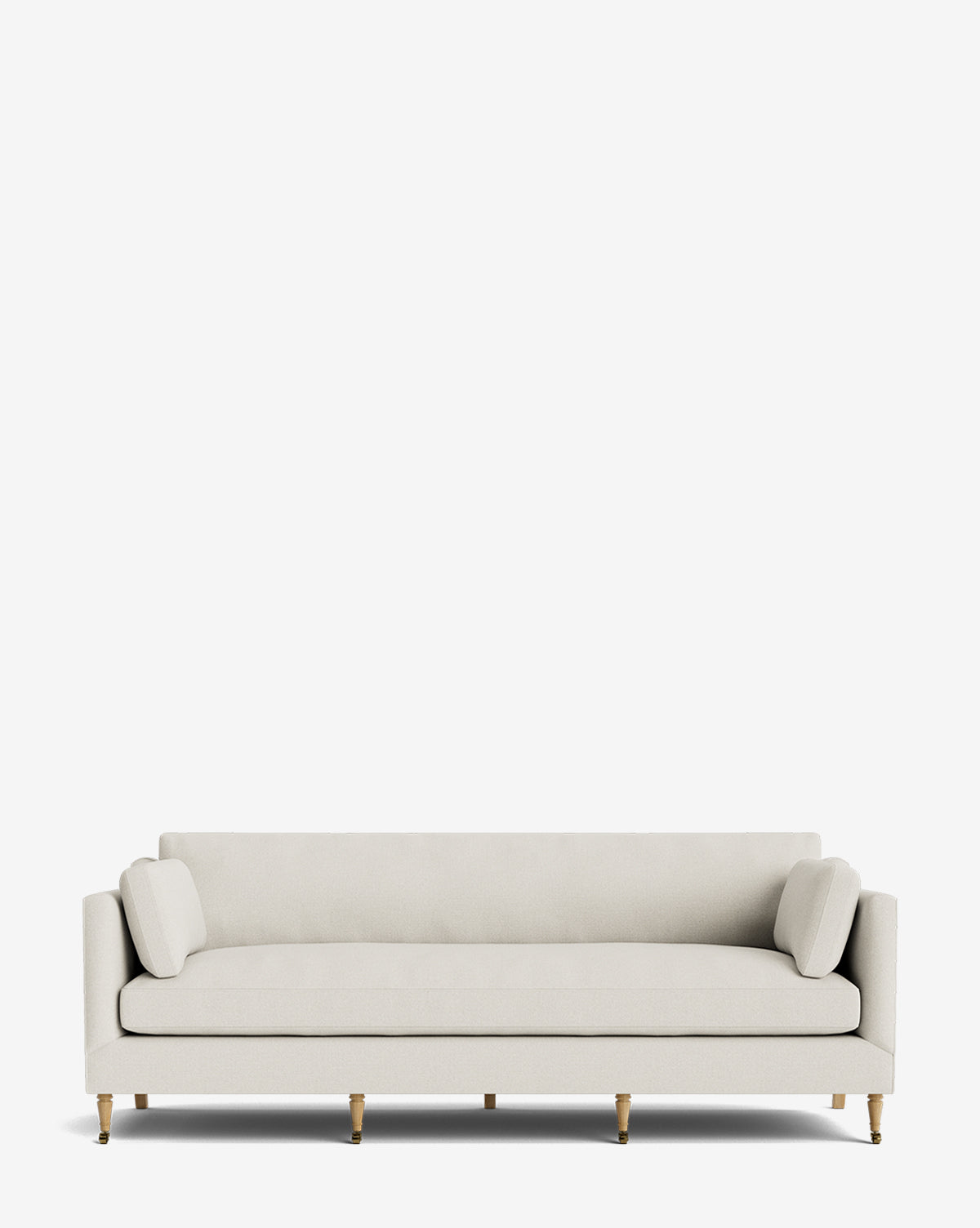 The Haverford Upholstered Sofa 90 is a modern, light beige handcrafted sofa with straight arms, two matching round cushions, and wooden legs with brass tips, shown against a plain white background by McGee & Co.