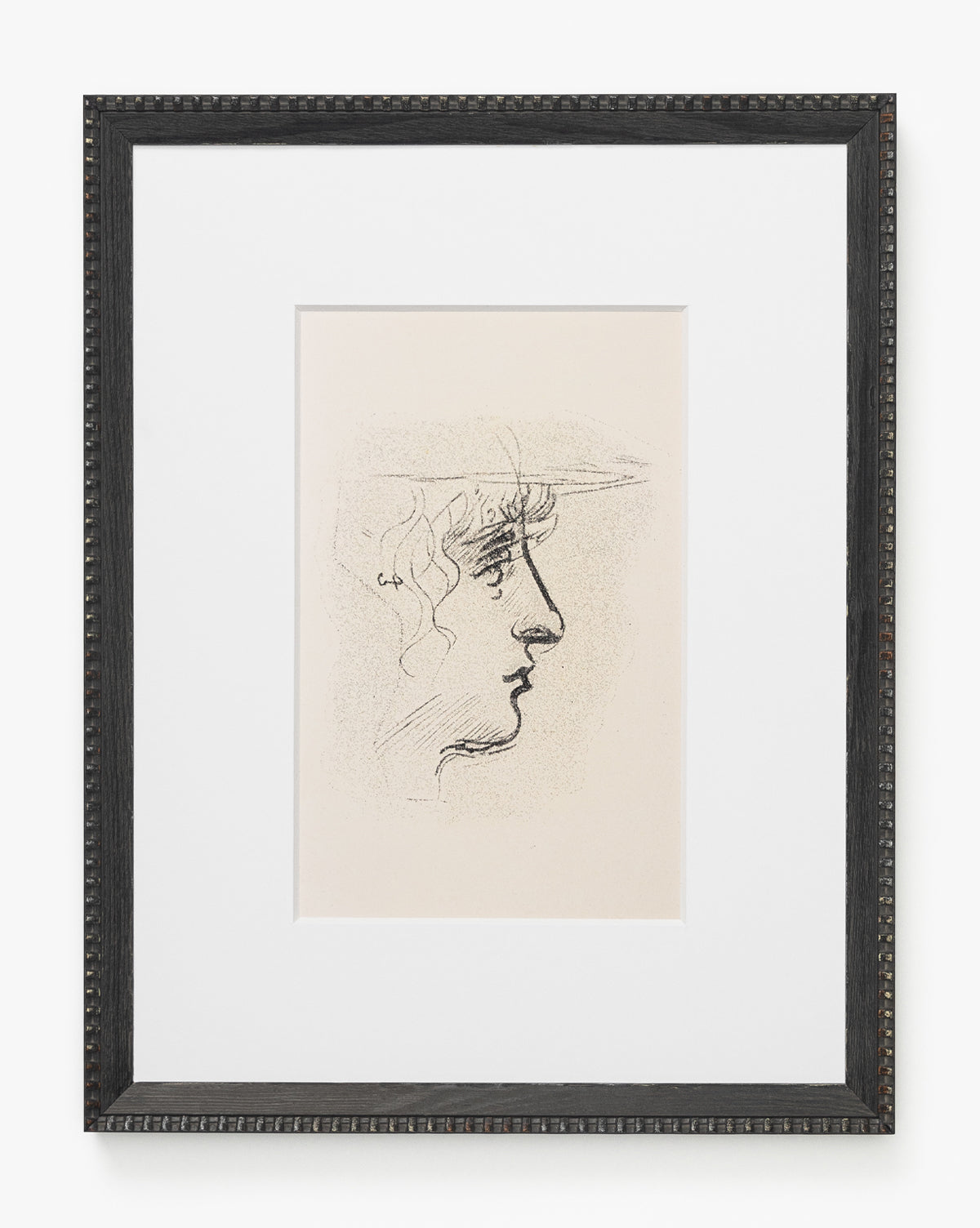 Head Study is a framed sketched portrait featuring a minimalist line drawing of a persons profile, facing right. Expressive lines depict long, wavy hair and facial features, set in a white mat and dark textured frame, by McGee & Co.