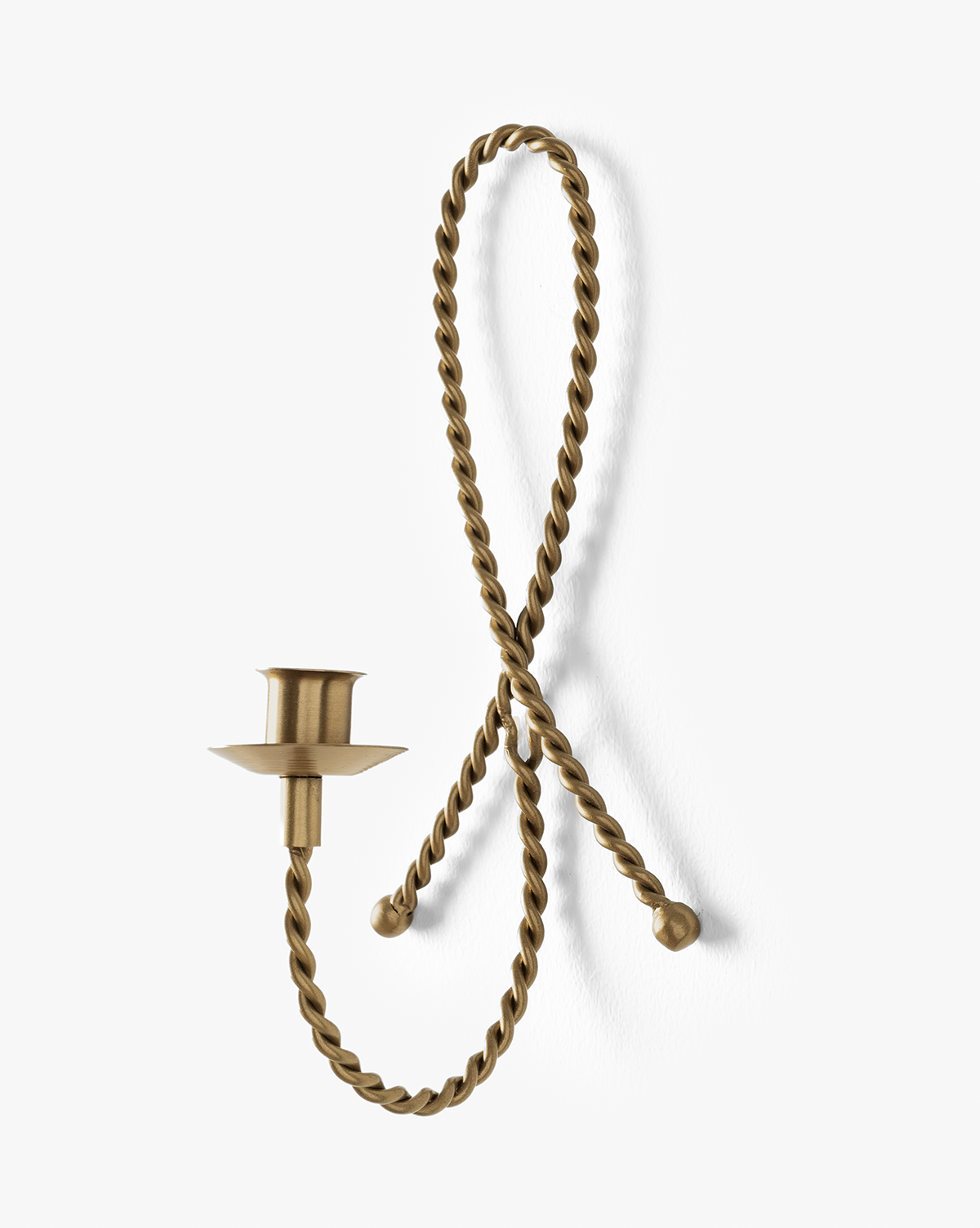 The Hearst Taper Holder is a brass candle holder with a twisted, rope-like loop that mounts to the wall at two points, featuring an elegant taper extension from the lower left side, by McGee & Co.