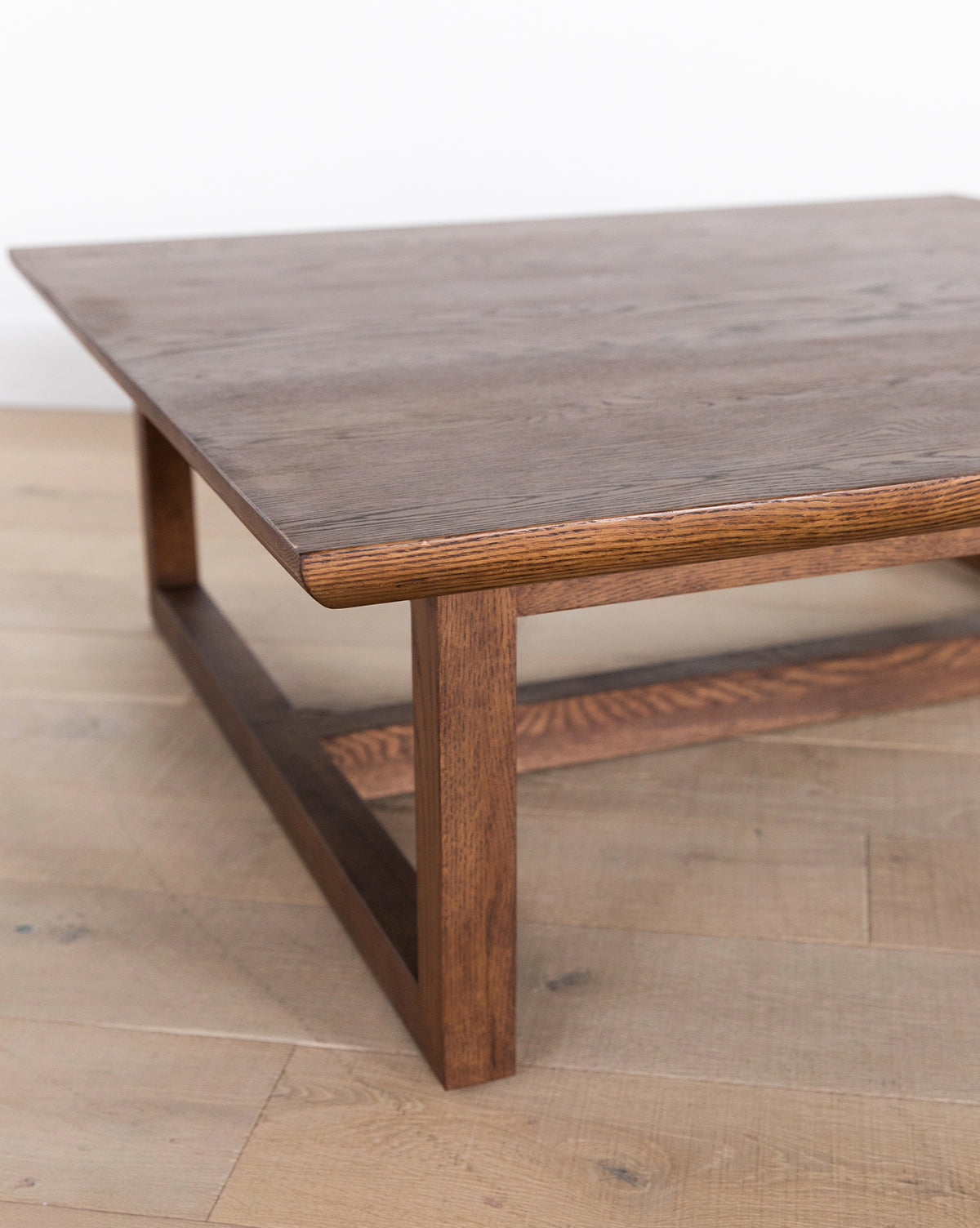 The Herrin Coffee Table boasts a rectangular solid oak top and sturdy square legs, bringing modern style to any space, especially on light wood floors with a white wall backdrop, by McGee & Co.