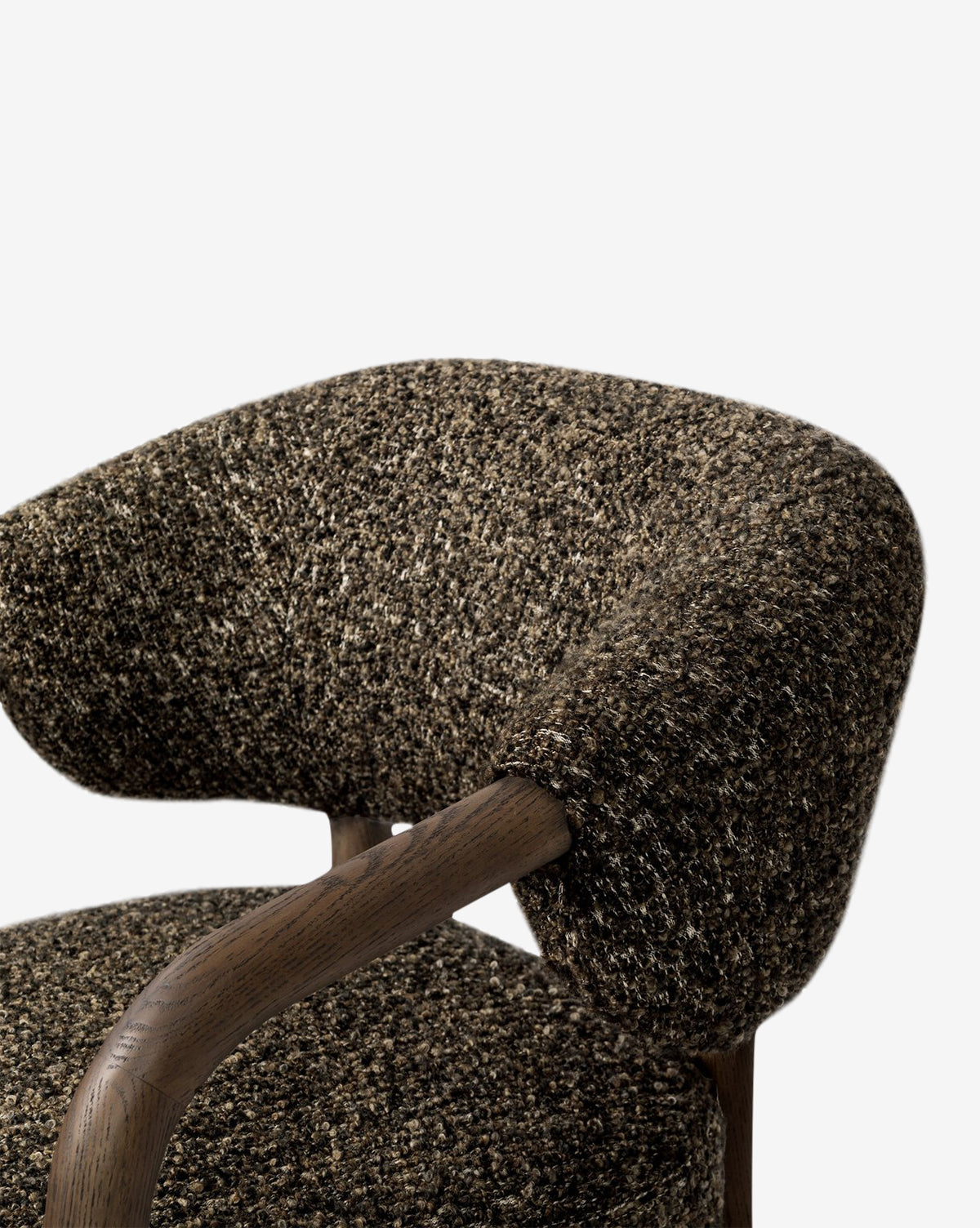 Close-up of the Holstein Lounge Chair, featuring a curved upholstered backrest and seat in textured brown fabric, wooden armrests, and a solid oak frame with a contemporary design, set against a plain white background, by McGee & Co.
