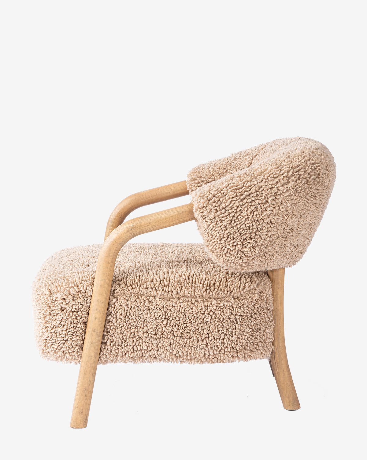 The Holstein Lounge Chair features a solid oak frame, light wooden legs, and thick beige upholstery that mimics faux Mongolian shearling. It has a rounded backrest and a cushioned seat for modern comfort, by McGee & Co.