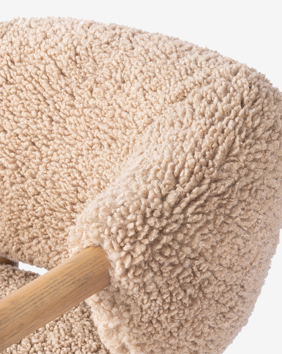 Close-up of the Holstein Lounge Chair, featuring a solid oak frame and plush, textured beige upholstery resembling faux Mongolian shearling on the armrest and backrest, by McGee & Co.