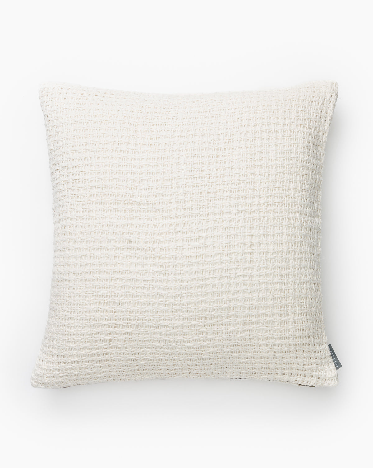 The Ingersoll Pillow Cover is a square, off-white neutral pillow cover with a textured woven pattern and a small fabric tag on the bottom edge, shown against a plain white background by McGee & Co.