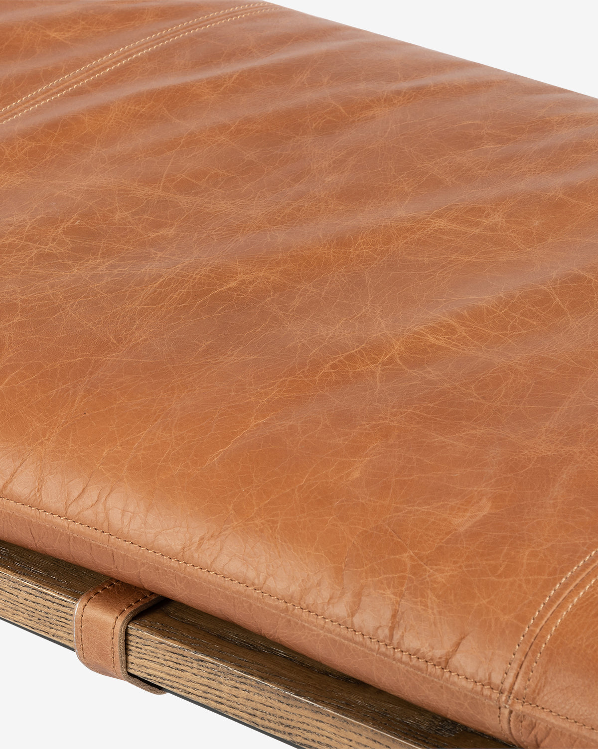 Close-up of the Jagger Accent Bench: tan leather cushion with visible stitching and natural texture, resting on a wooden frame—an elegant bench ideal for transitional interiors, by McGee & Co.
