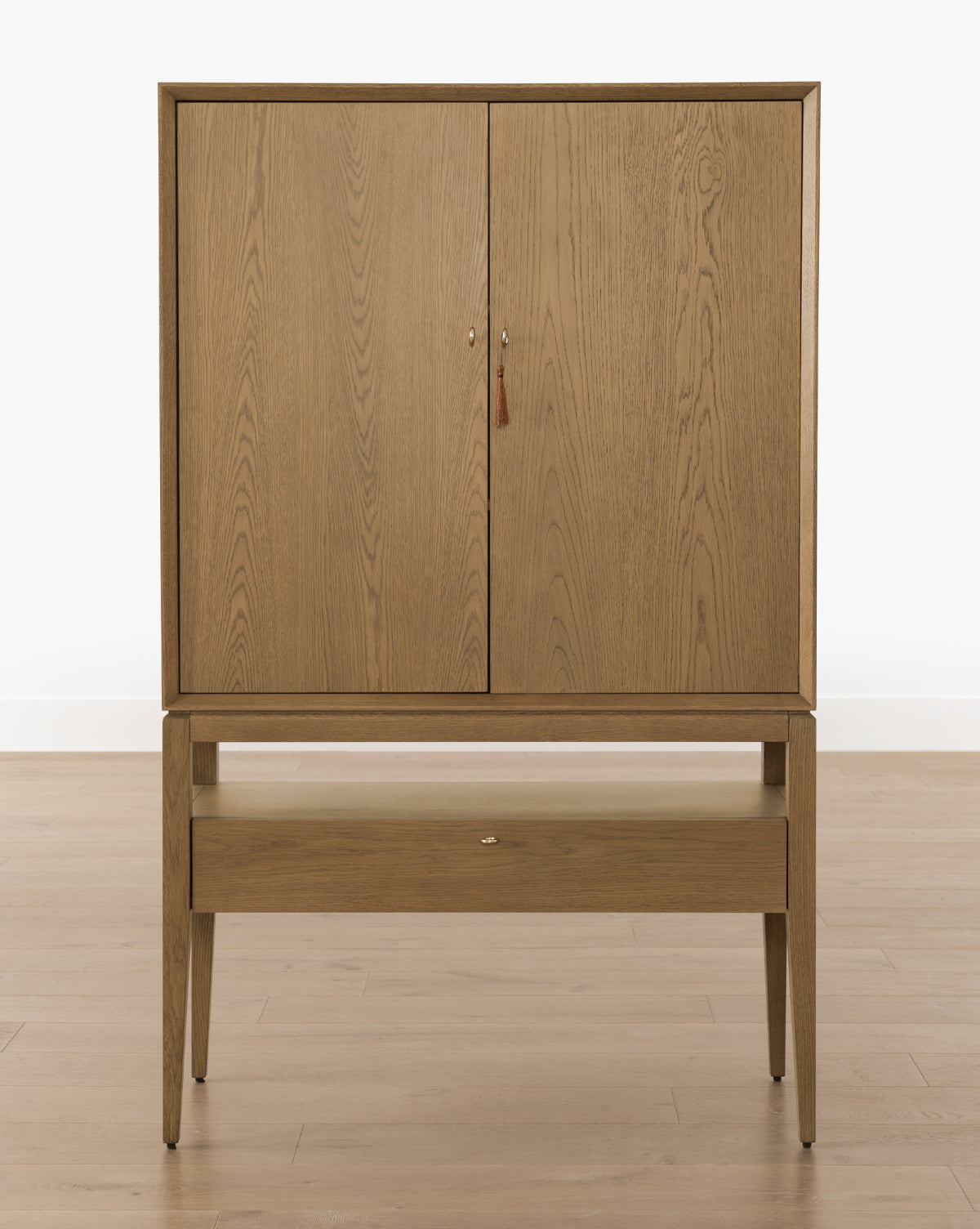 The Jahnsen Cabinet showcases a traditional design with two doors and a single drawer, finished in warm honey oak, by McGee & Co.