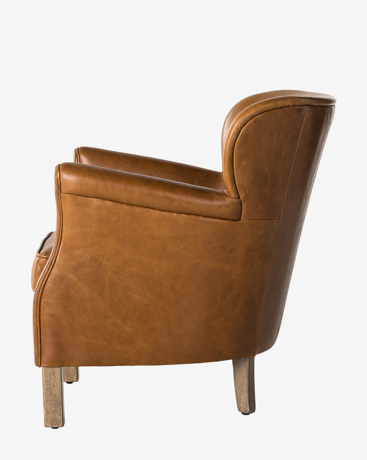 The Jarah Lounge Chair, shown from the side against a white background, features brown top-grain leather upholstery, wooden legs, curved armrests, and a cushioned back by McGee & Co.