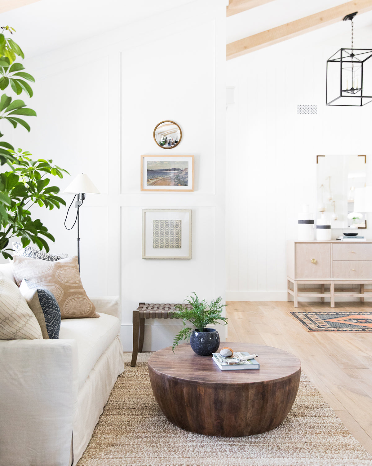 Bright, airy living room with white walls, neutral pillows, and light wood floors. The abstracted pattern of Repetition 8 on the bench adds interest, while green plants and framed artwork create a cozy, inviting space.