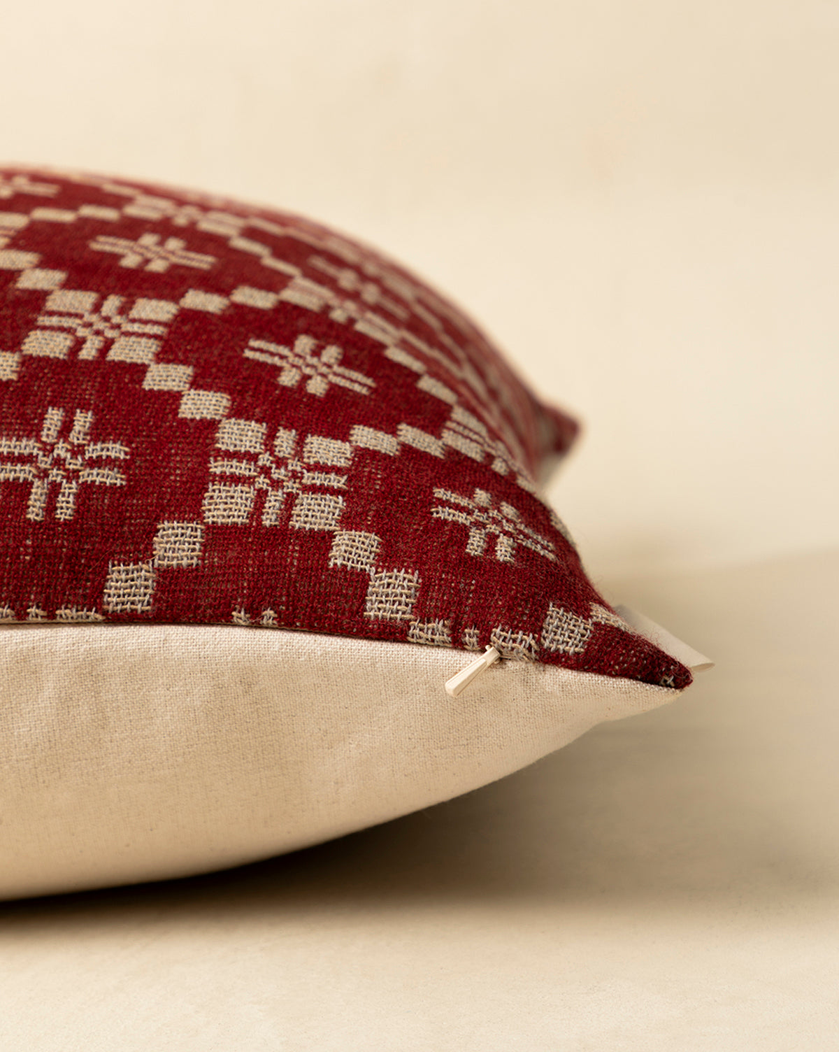 The Jude Pillow Cover features a red and beige geometric woven top, plain beige bottom, and a delicate bow at one corner—ideal for seasonal styling. Shown here on a light surface in close-up detail, by McGee & Co.