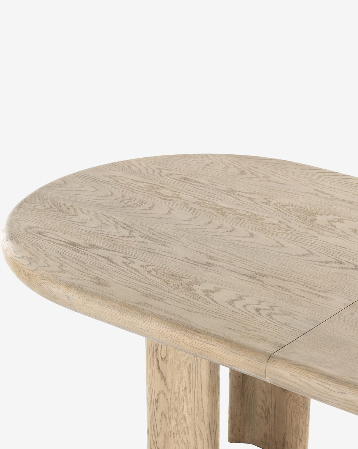 A close-up of the Juliana Extension Dining Table, featuring a smooth, rounded solid oak edge, visible wood grain, and two sturdy legs against a white background, by McGee & Co.