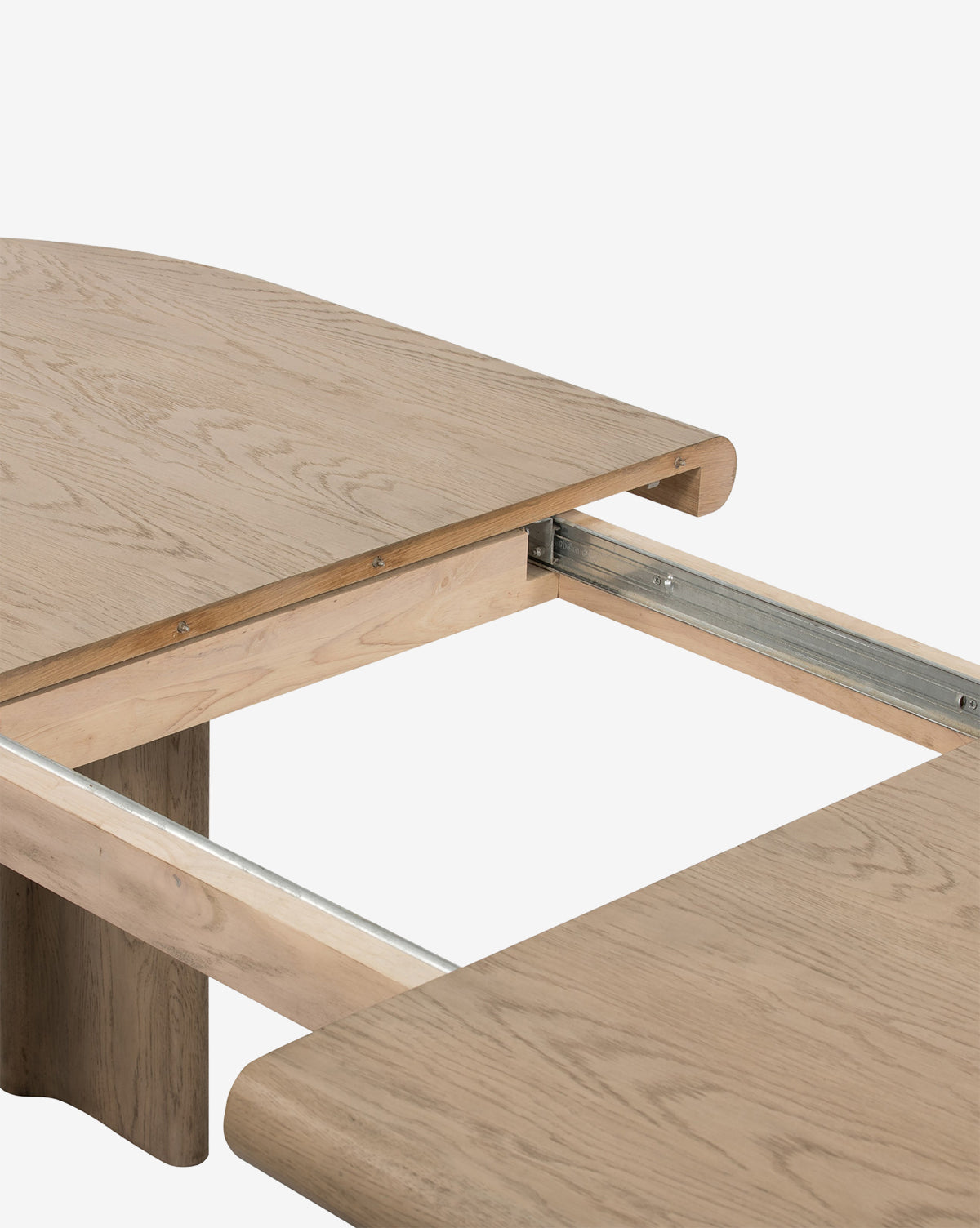A close-up of the Juliana Extension Dining Table, partially open to reveal metal extension rails and space for a middle leaf, by McGee & Co. The light natural oak finish highlights its modern tabletop design.