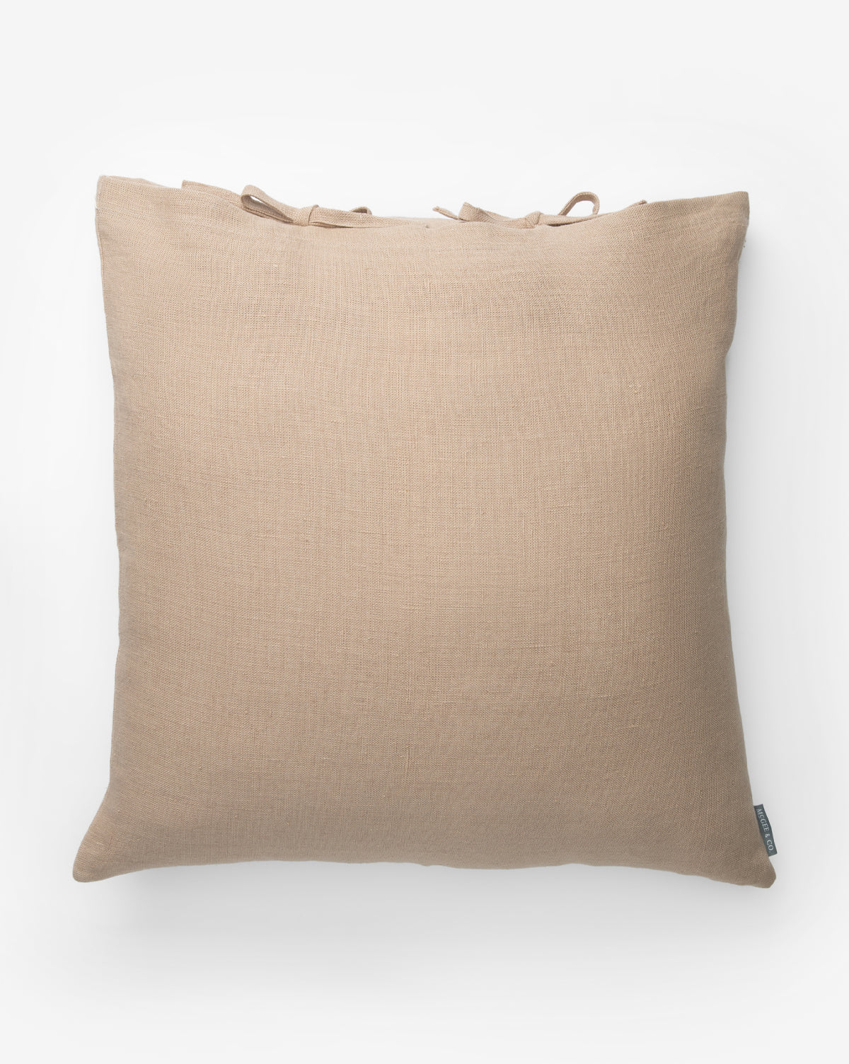 The Kara Linen Pillow Cover is a square, beige cover with a soft texture, shown from above on a white background. It features small tie accents along the top edge for subtle decoration by McGee & Co.