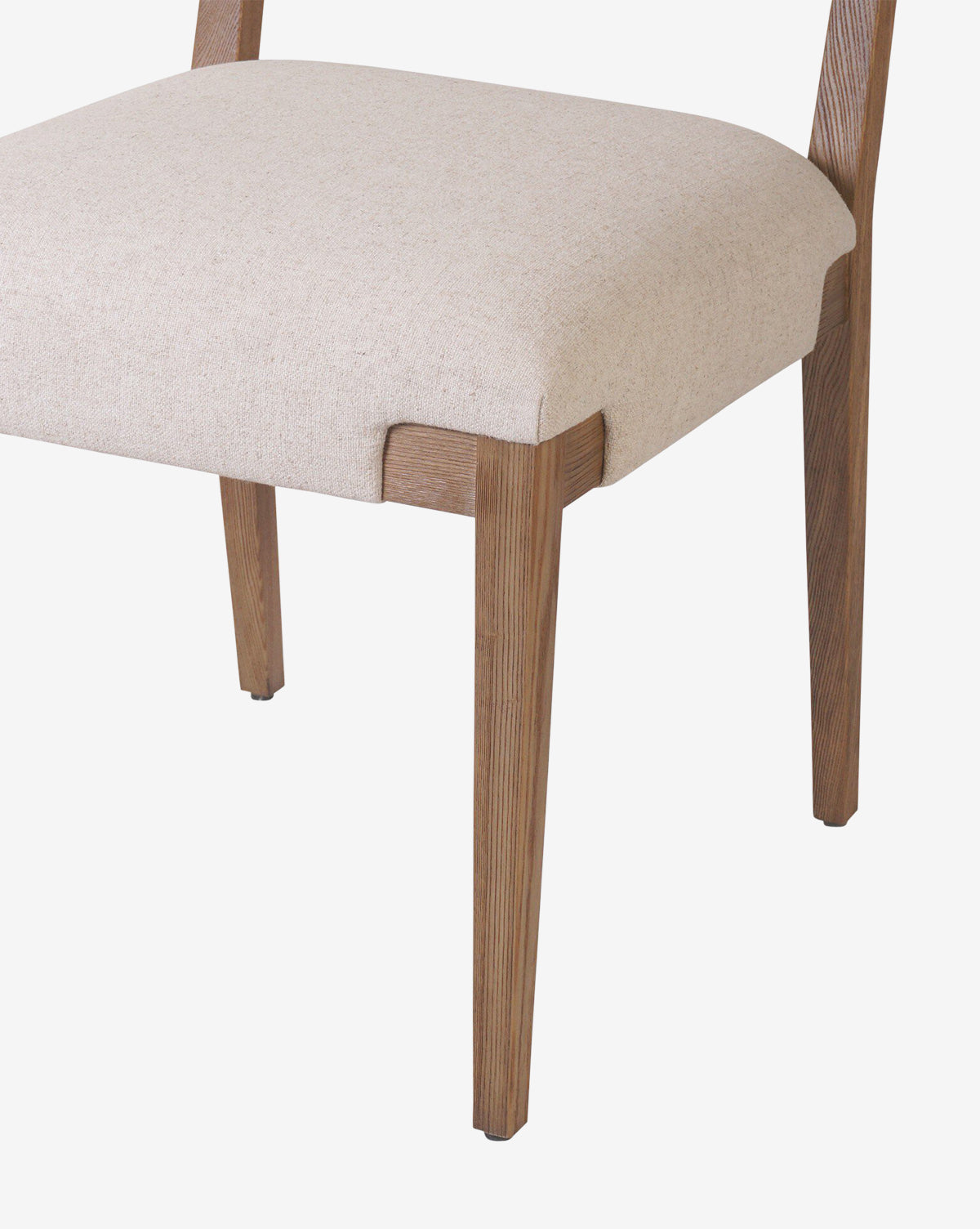 A close-up of the Kennebec Dining Chair, featuring light beige performance fabric upholstery and sturdy ash legs, showcases the seat and partial legs against a white background by McGee & Co.