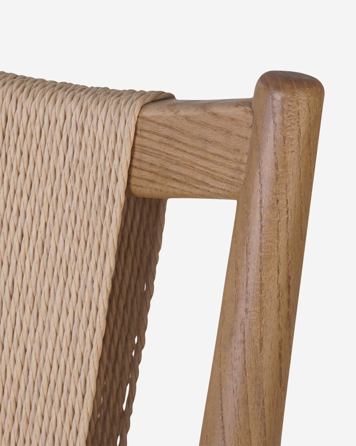 Close-up of the Kimball Dining Chair features its smooth wood frame with a light brown woven seat and backrest, showcasing the weaves texture against a white background, by McGee & Co.
