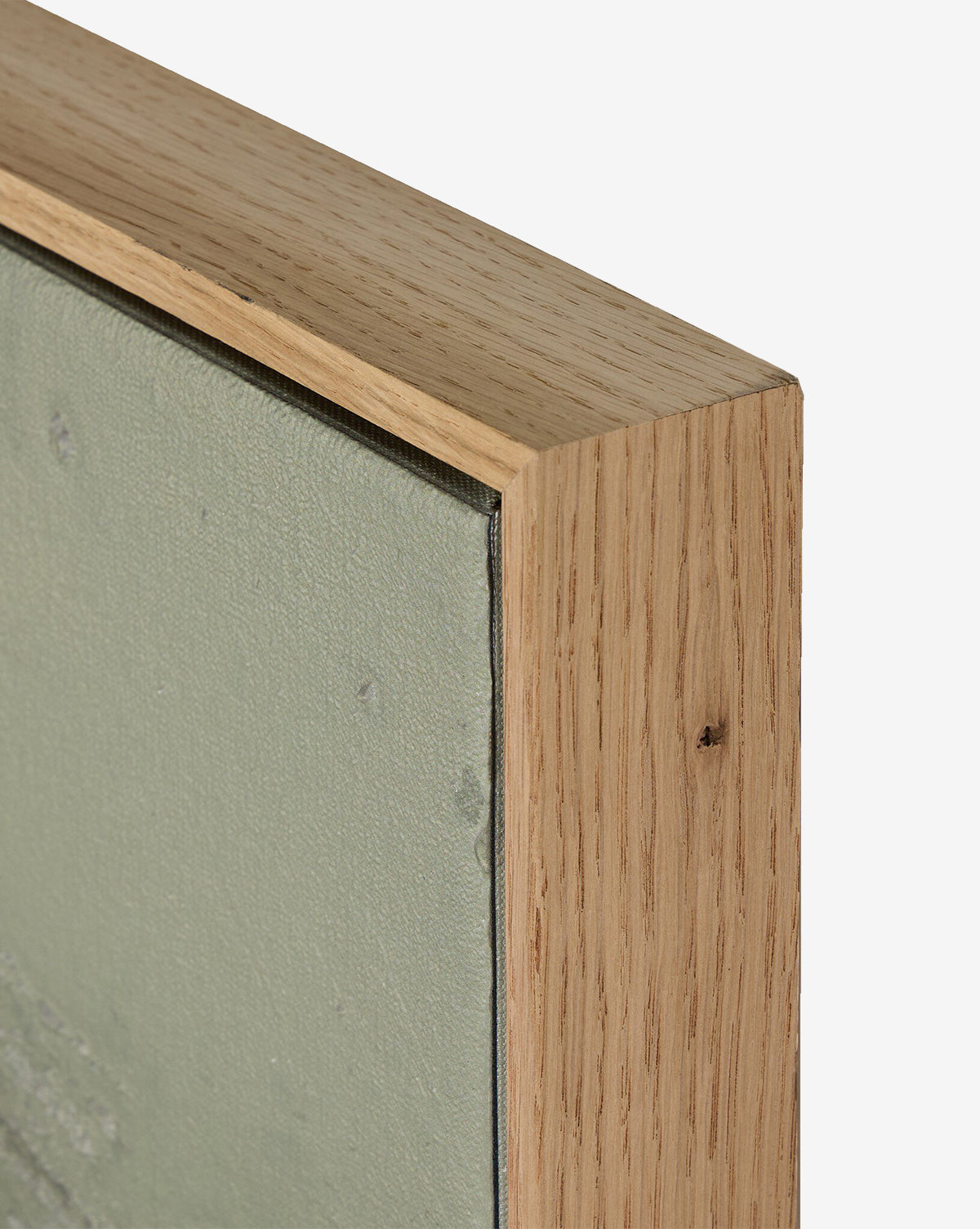 Close-up of the top corner of a white oak frame encasing Knowledge Of The Stream by Tyler Guinn, a canvas with muted green abstract art, set against a plain white background—ideal for contemporary decor, by McGee & Co.