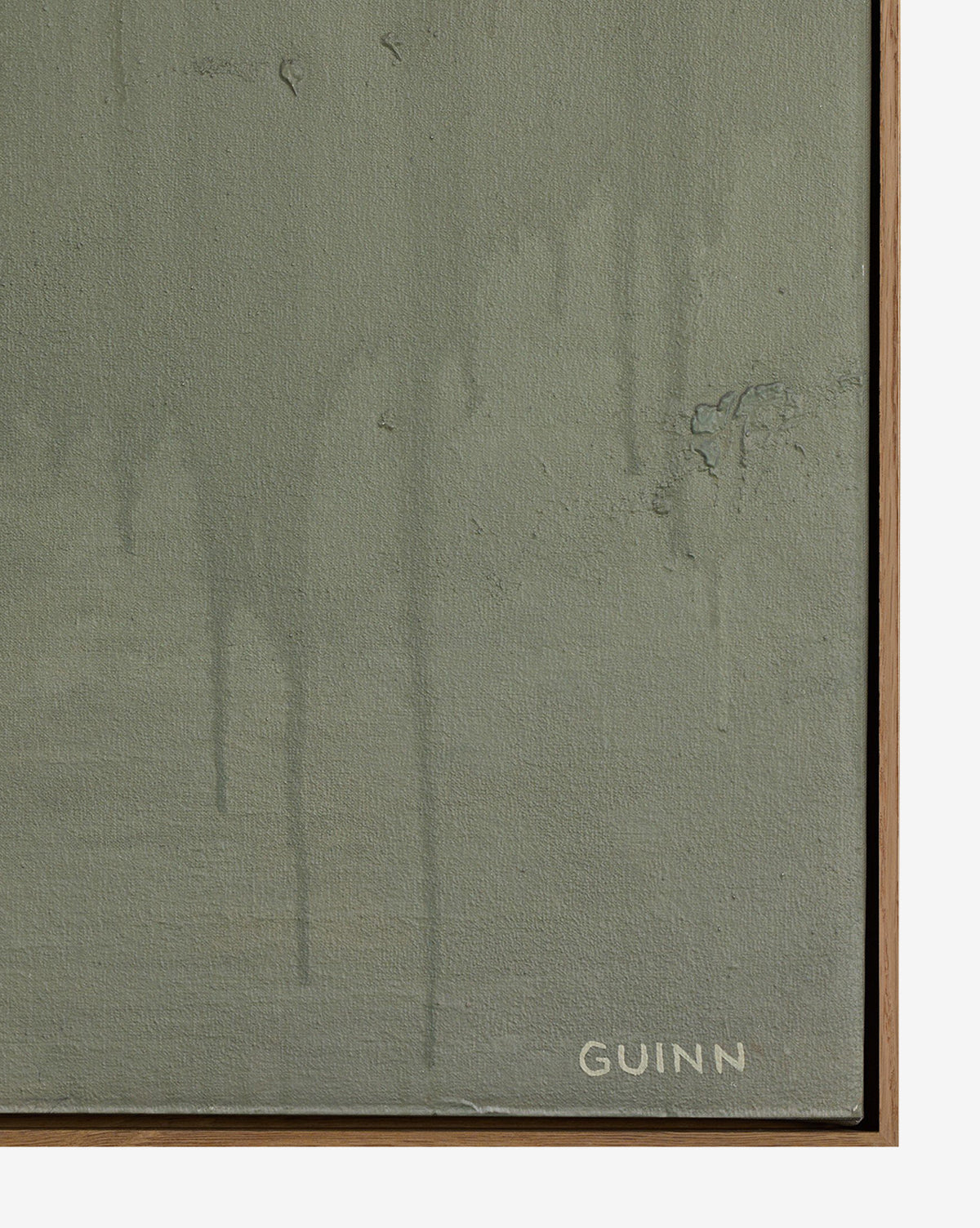 A close-up of Knowledge Of The Stream by Tyler Guinn shows a greenish-gray textured canvas with faint paint drips, subtle surface imperfections, and the artist’s white signature at the bottom right, bordered by a thin white oak frame by McGee & Co.