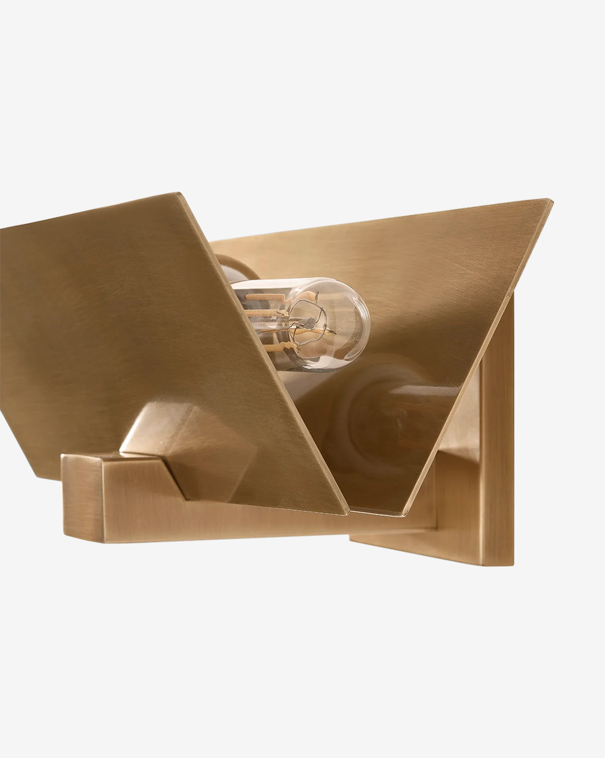 A close-up of the Lander Wall Sconce, a modern fixture with angular geometric panels in patina brass and an exposed tubular bulb, displayed against a white background, by McGee & Co.