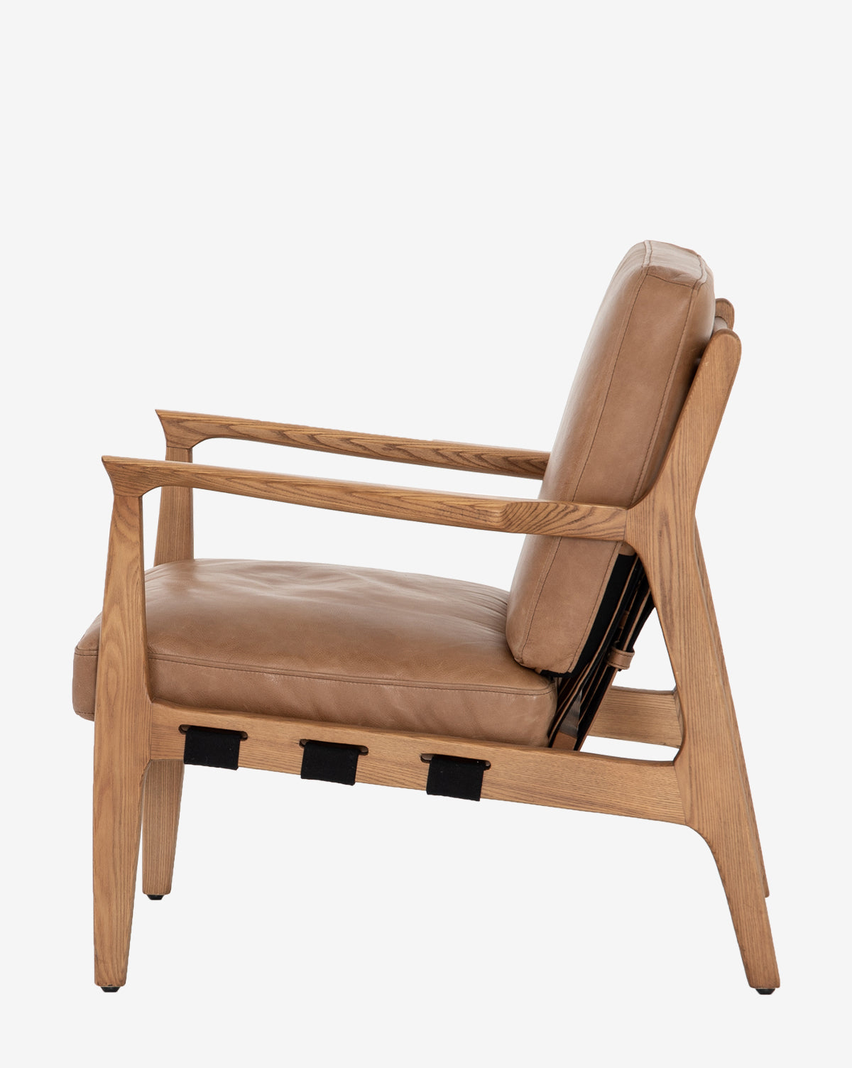 Side view of the Lanston Lounge Chair with an ash wood frame, angled legs, light brown leather seat and back cushions, and black straps under the seat, set against a white background by McGee & Co.