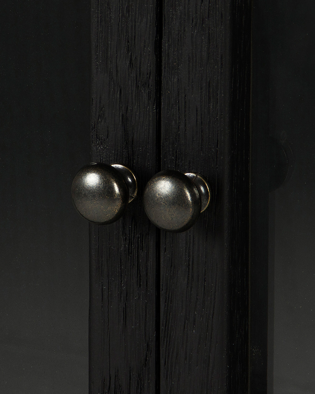 Close-up of two round metallic knobs on dark drift oak doors of the Lawley Cabinet, showing a subtle reflective surface—an elegant detail for your space, by McGee & Co.
