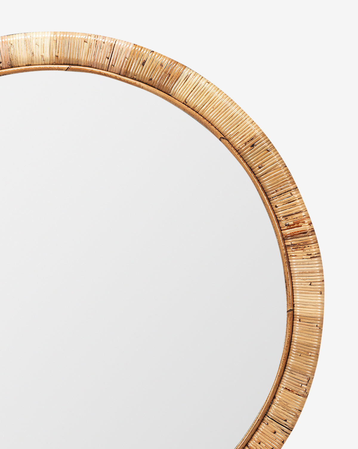 A close-up of the Lenore Wall Mirror featuring a round shape and woven rattan frame, shown against a white background. The visible upper right section highlights its natural elements and transitional design appeal, by McGee & Co.