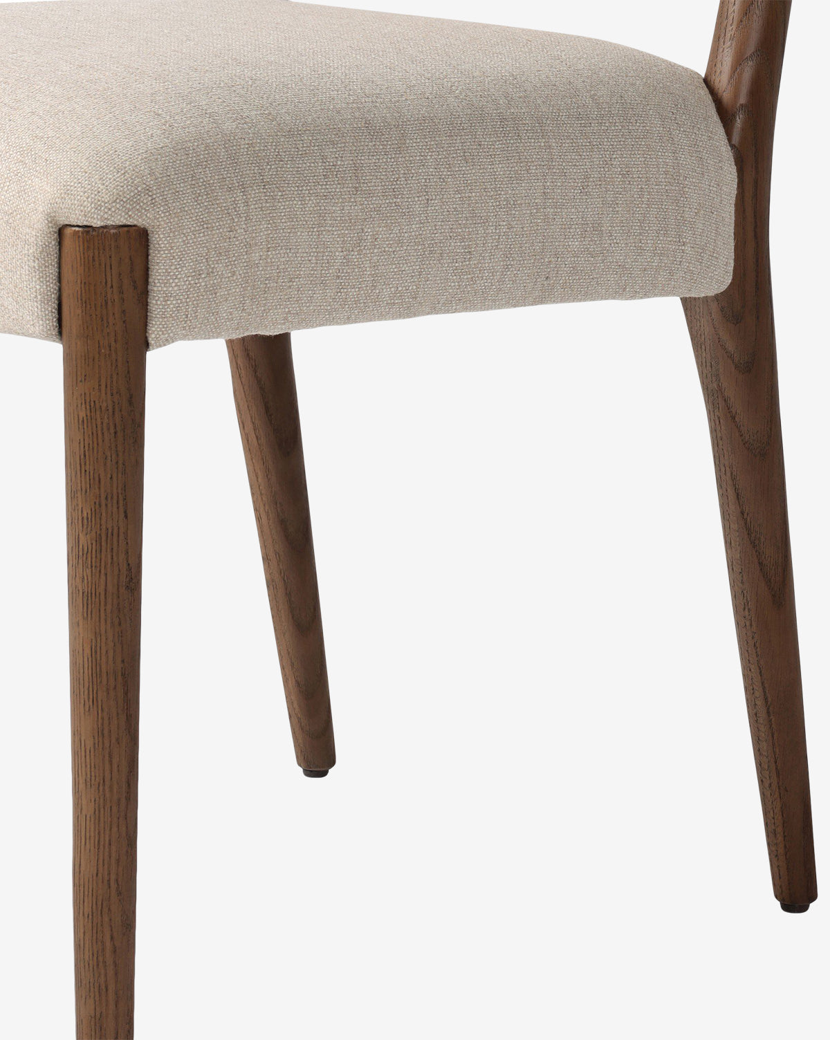 Close-up of the Leola Dining Chair, showcasing its beige upholstered seat and two natural-finish oak legs, set against a plain white background, by McGee & Co.