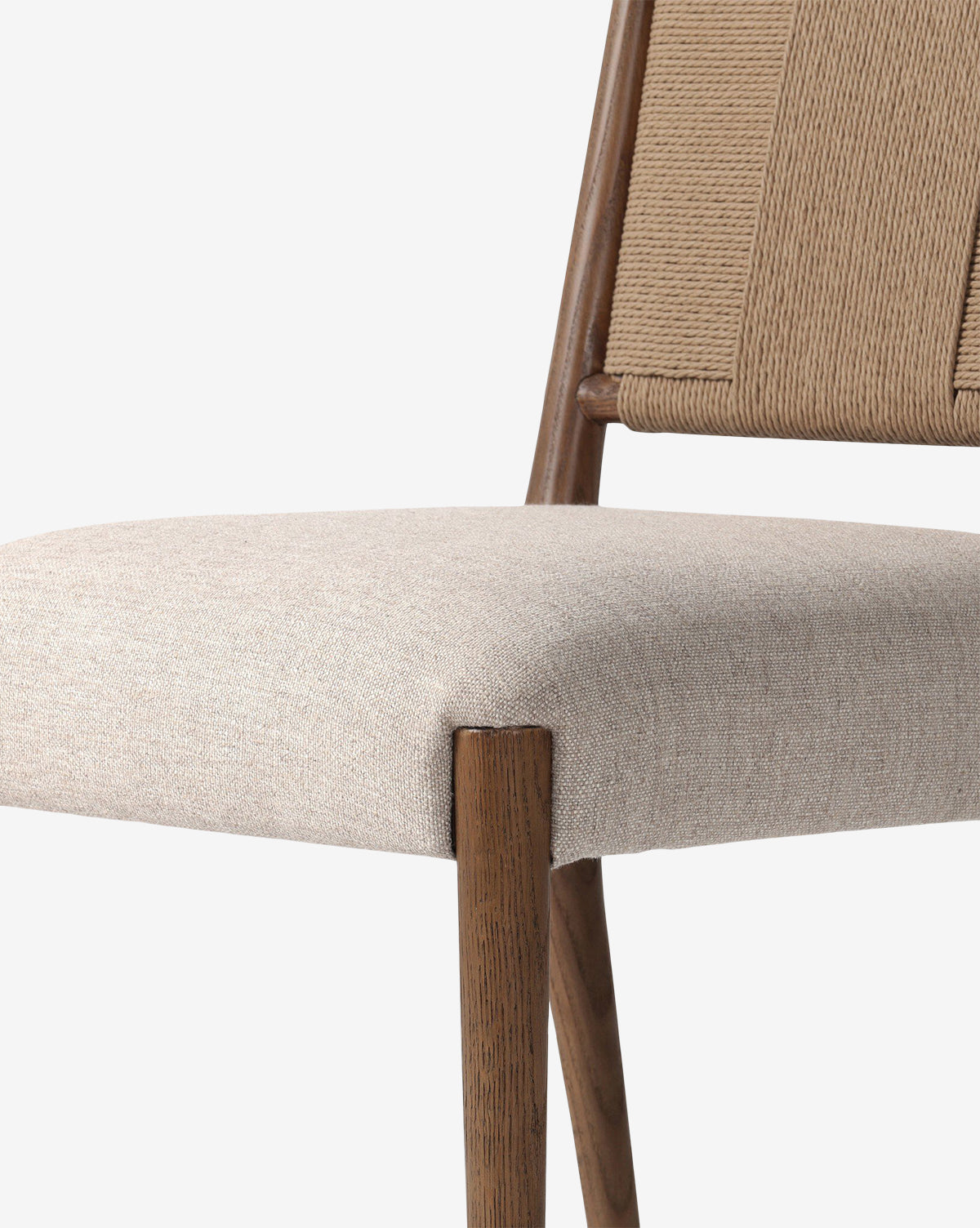Close-up of the Leola Dining Chair featuring an oak frame, wooden legs, a light beige upholstered seat, and a woven rush backrest made with thick tan cords, by McGee & Co.