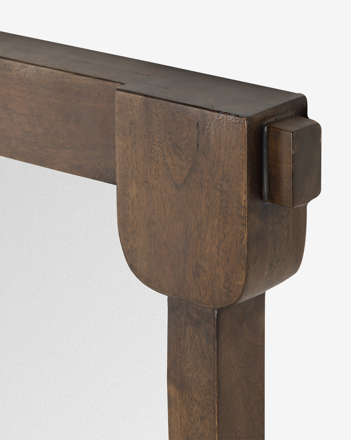 Close-up of the upper corner of the Letterly Floor Mirrors solid acacia wood frame in rich brown, with smooth, rounded edges and a distinctive joint—showcasing traditional craftsmanship. Partial view of the mirror glass included, by McGee & Co.