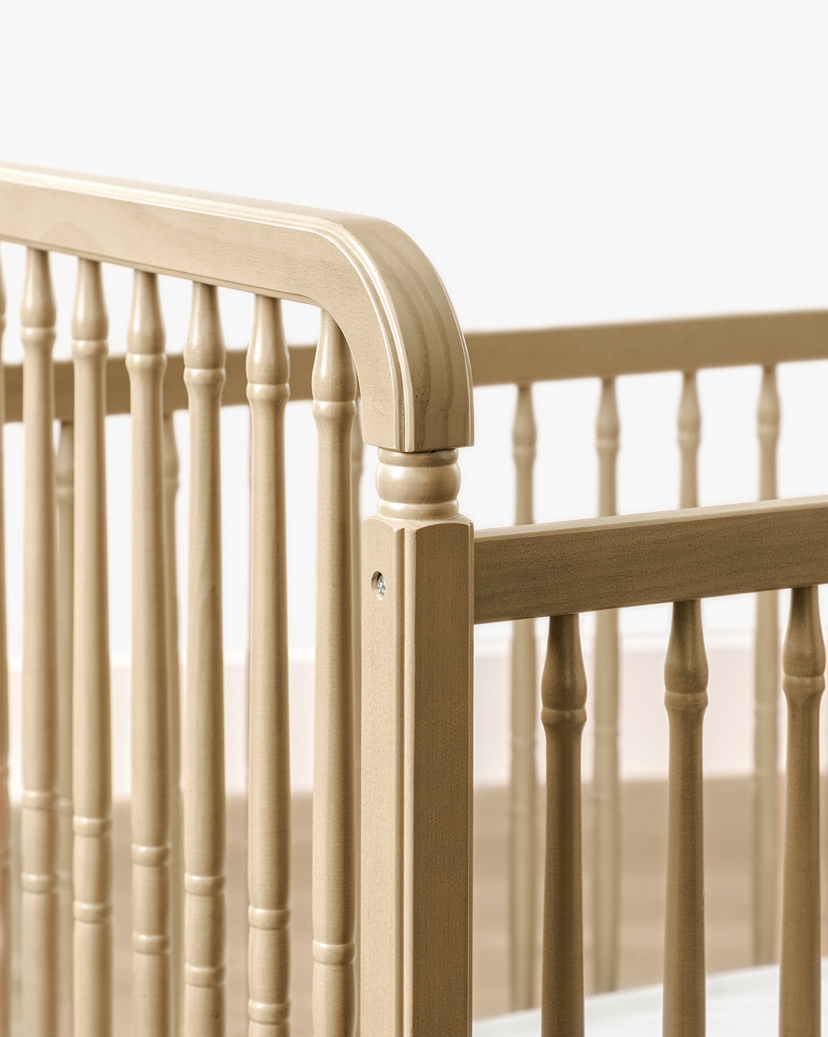 Close-up of the Liberty 3-in-1 Convertible Spindle Crib w/Toddler Bed Conversion Kit, crafted from solid pine with vertical slats and rounded headboard corners, shown against a white background by McGee & Co.