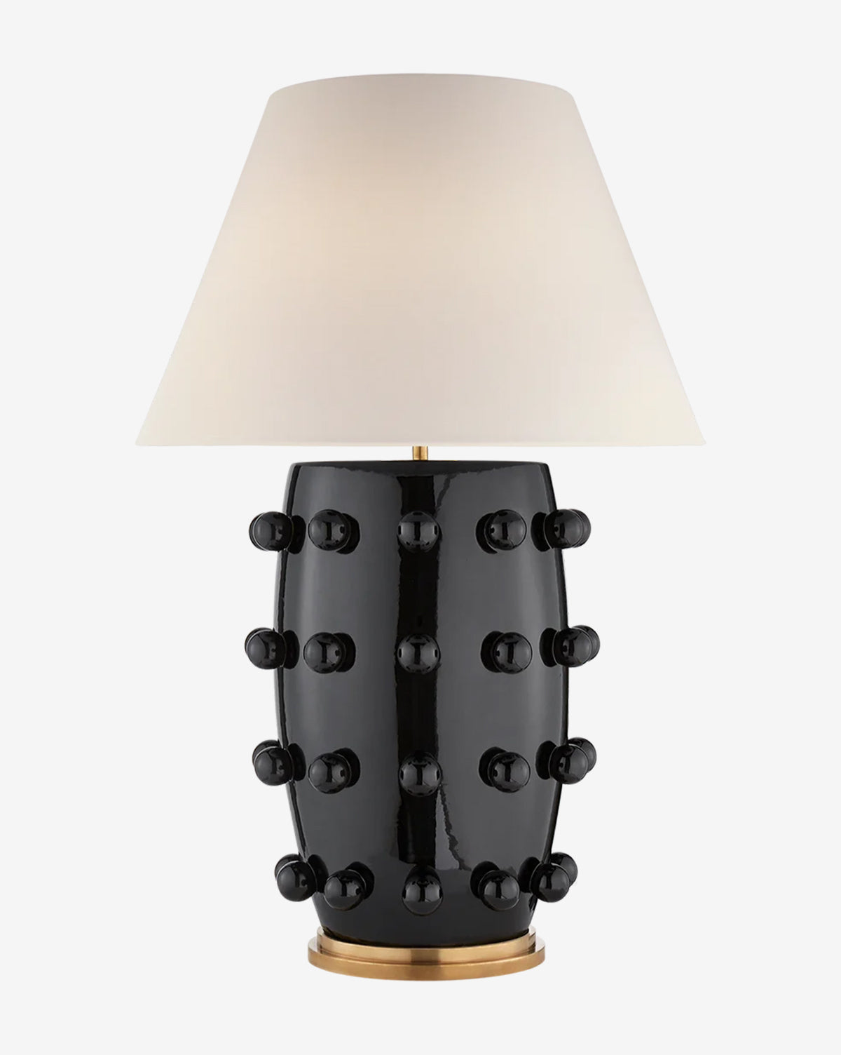 The Linden Table Lamp has a glossy black porcelain base with circular knobs, a gold bottom accent, and a large white linen shade for modern style, by McGee & Co.