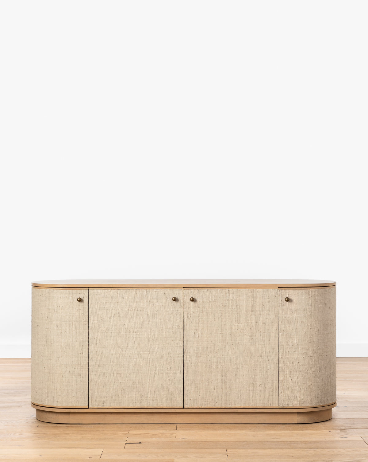 The Linu Woven Sideboard, with four doors and rounded edges, features a light wooden top and base, by McGee & Co. It stands on a wooden floor against a plain white background.