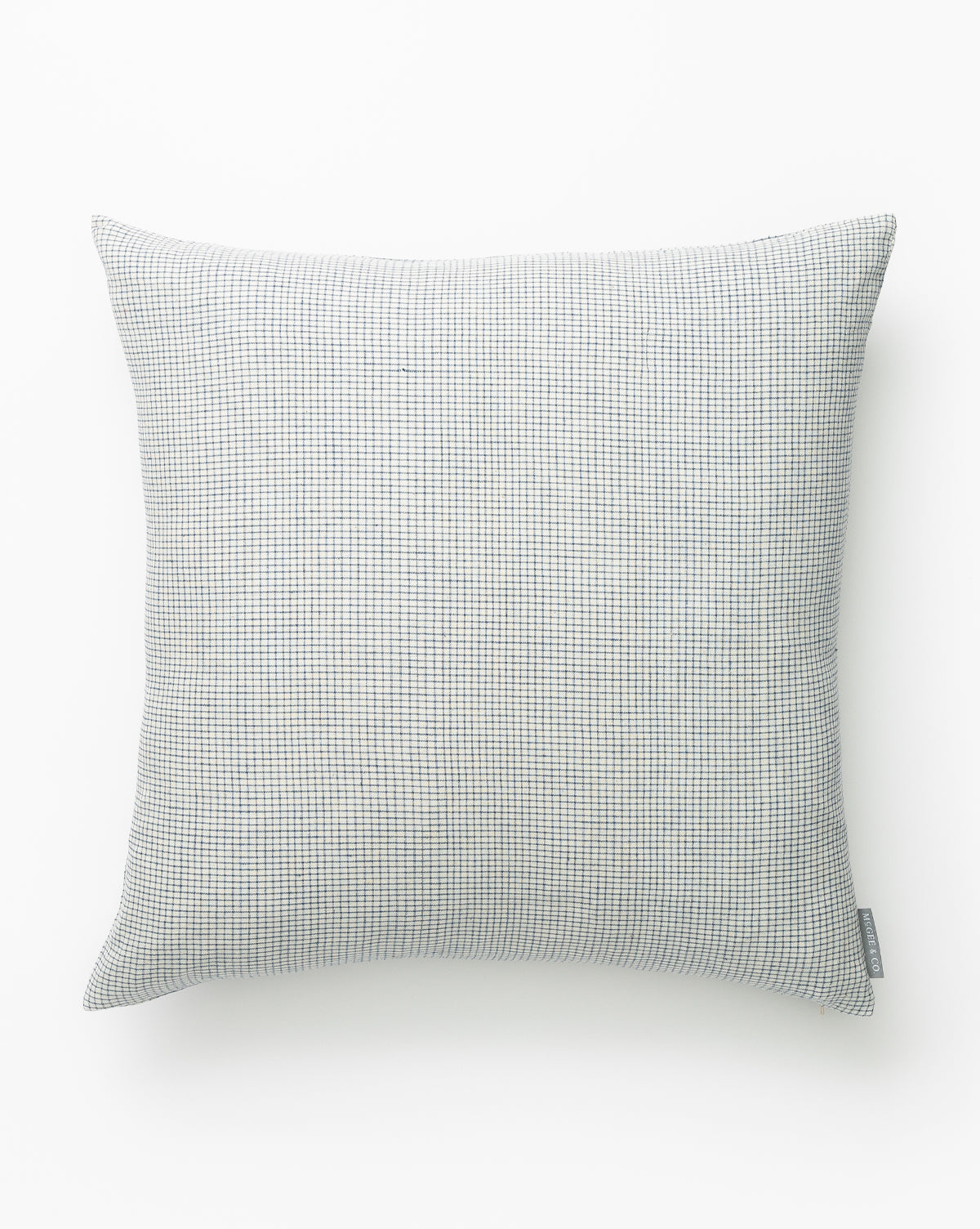 The Luther Pillow Cover features a square shape in blue and cream with a small grid pattern, shown against a white background. A small fabric tag on the side adds a subtle accent, making it a stylish addition to any room by McGee & Co.