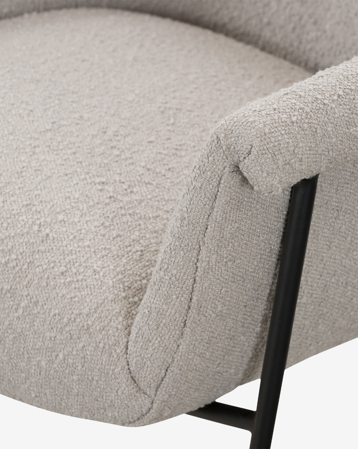 Close-up of the Sabbath Dining Chair with light beige performance fabric upholstery, black metal legs, and a curved armrest, shown against a white background by McGee & Co.