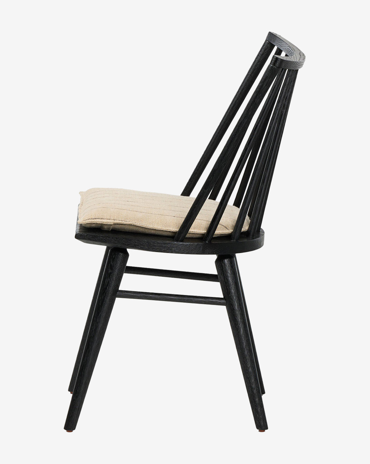 Side view of the Madison Dining Chair in black wood, featuring angled legs, a slatted backrest, and a light beige seat cushion, set against a plain white background by McGee & Co.