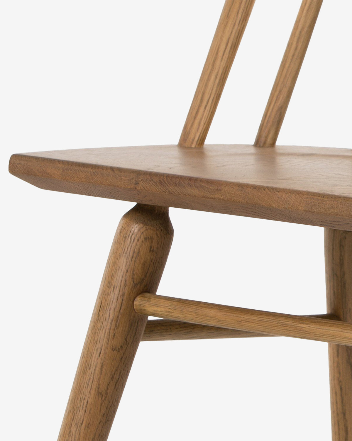 Close-up of the Madison Dining Chair, highlighting part of the seat, two vertical backrest supports, and angled legs with a horizontal support, all crafted from light brown wood, by McGee & Co.