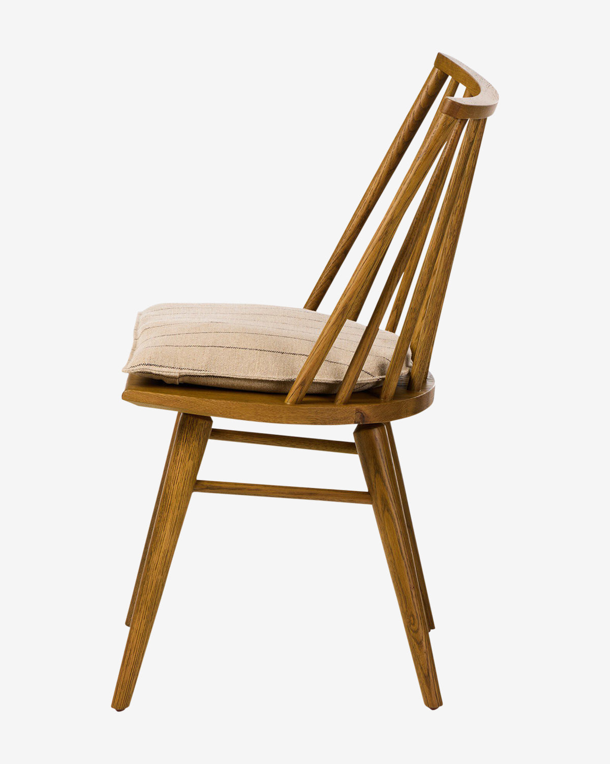 Side view of the Madison Dining Chair showing angled backrest spindles and a rectangular beige seat cushion. This oak chair features four legs and a minimalist mid-century modern design, by McGee & Co.