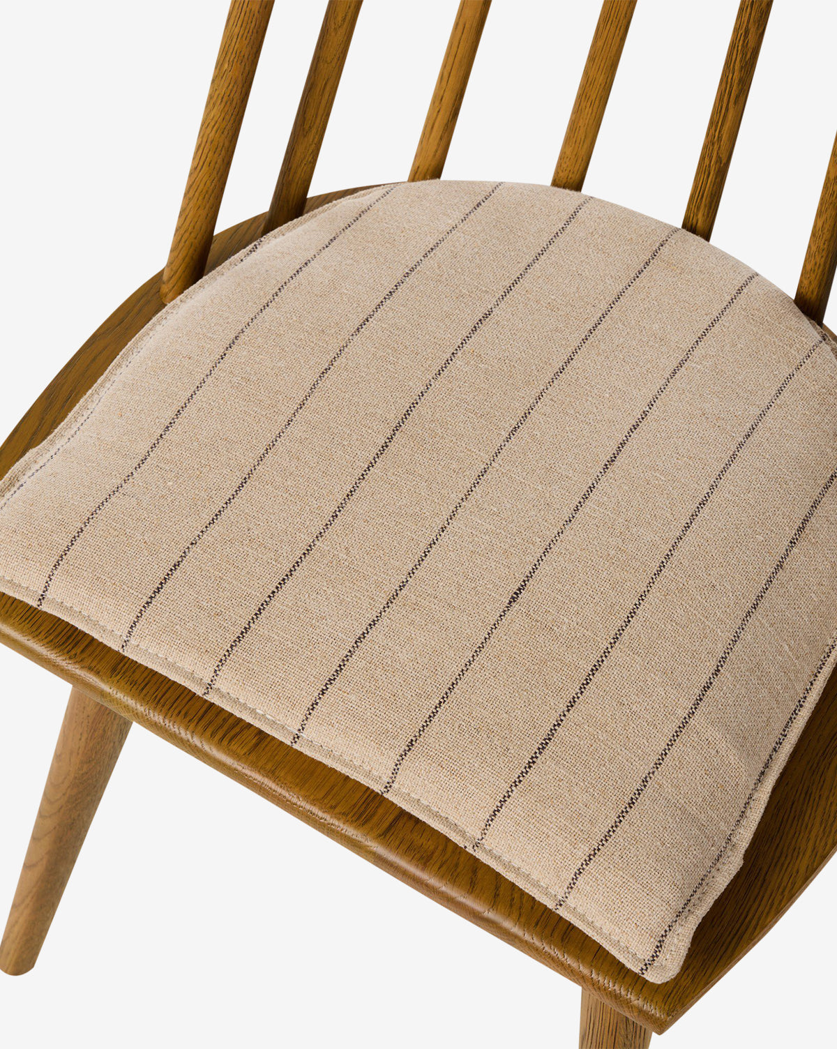 Close-up of the Madison Dining Chair: a modern oak design with vertical wooden slats, angled legs, and a light beige cushion featuring thin, dark stripes, by McGee & Co.